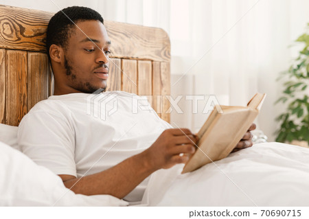 Black Man Enjoying Reading Book Lying In Bed At Home Black Man Enjoying Reading Book Lying In Bed At Home 70690715