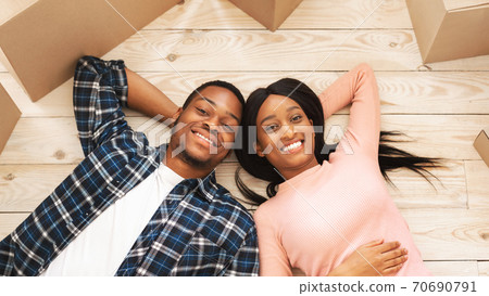 Positive young African American family with carton boxes having rest on moving day, overhead view Positive young African American family with carton boxes having rest on moving day, overhead view 70690791