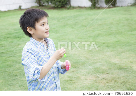 Boy playing with soap bubbles Boy playing with soap bubbles 70691620