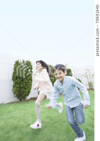 姐妹和兄弟在花園裡奔跑 70691640