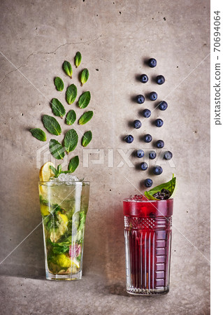 Two summer cocktails at concrete grey background. mohito and blueberry tea. Fresh cold drinks Two summer cocktails at concrete grey background. mohito and blueberry tea. Fresh cold drinks 70694064