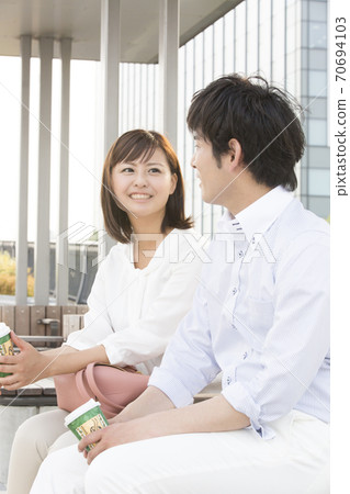 Couple sitting on a bench and having a conversation Couple sitting on a bench and having a conversation 70694103