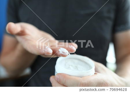 Man's hand holds jar with a white substance inside. Man's hand holds jar with a white substance inside. 70694628