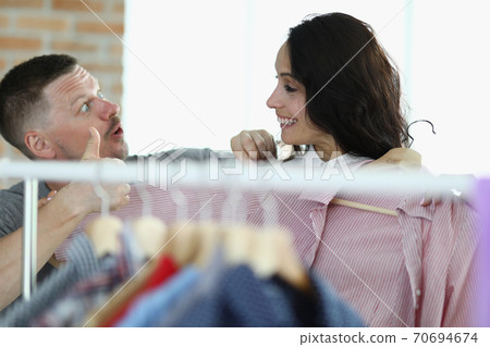 Man and woman are smiling at each other next to hanger with things Man and woman are smiling at each other next to hanger with things 70694674