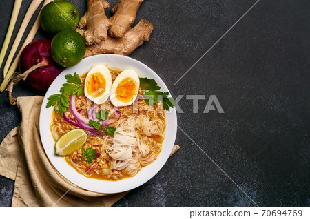 Mohinga or Burmese Fish Noodle Soup in white plate on dark table top. 70694769