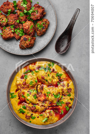 Punjabi Kadhi Pakora in gray bowl on concrete table top. Kadhi Pakoda is indian cuisine curry dish. Punjabi Kadhi Pakora in gray bowl on concrete table top. Kadhi Pakoda is indian cuisine curry dish. 70694807