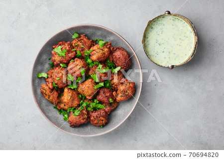 Veg Pakora in gray bowl on concrete table top. Pakoda is indian cuisine appetizer deep fried dish Veg Pakora in gray bowl on concrete table top. Pakoda is indian cuisine appetizer deep fried dish 70694820