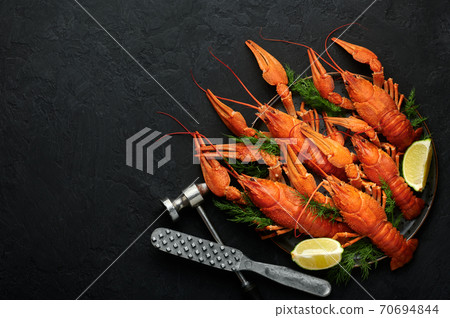 Boiled Crayfish on black plate on dark slate table top. Red crawfish with green dill and lime Boiled Crayfish on black plate on dark slate table top. Red crawfish with green dill and lime 70694844