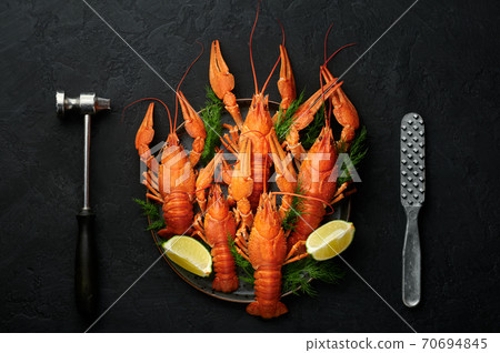 Boiled Crayfish on black plate on dark slate table top. Red crawfish with green dill and lime Boiled Crayfish on black plate on dark slate table top. Red crawfish with green dill and lime 70694845