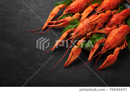 Boiled Crayfish on black plate on dark slate table top. Red crawfish with green dill and lime Boiled Crayfish on black plate on dark slate table top. Red crawfish with green dill and lime 70694847