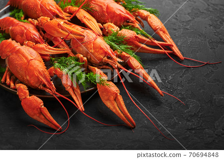 Boiled Crayfish on black plate on dark slate table top. Red crawfish with green dill and lime Boiled Crayfish on black plate on dark slate table top. Red crawfish with green dill and lime 70694848