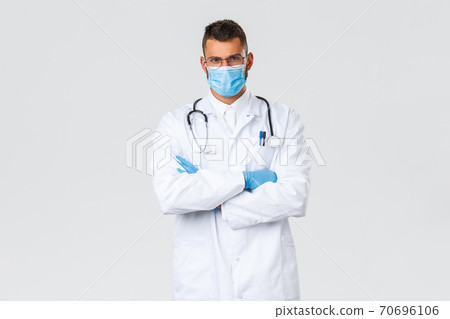 Covid-19, healthcare workers, pandemic and preventing virus concept. Serious determined doctor working with coronavirus patients, wearing protective personal equipment, medical mask and gloves Covid-19, healthcare workers, pandemic and preventing virus concept. Serious determined doctor working with coronavirus patients, wearing protective personal equipment, medical mask and gloves 70696106