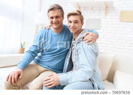 Dad hugged his son while they are sitting at home. Dad hugged his son while they are sitting at home. 70697638