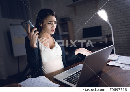 Young woman works late at night at work. 70697718