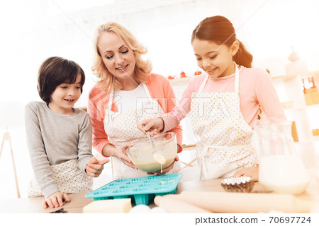 Little girl puts dough into molds and smiles. 70697724