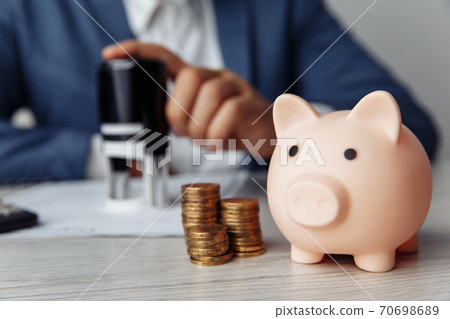 Pink piggy bank with stack of coins on desk in office. Save money and management financial concept 70698689