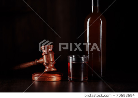 Bottle and glass with whisky and judge gavel, alcohol and crimes concept 70698694