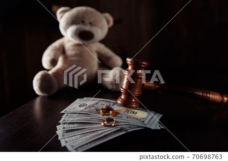 Wooden judge gavel, money banknotes, rings and teddy bear on a wooden table. Divorce and alimony concept Wooden judge gavel, money banknotes, rings and teddy bear on a wooden table. Divorce and alimony concept 70698763
