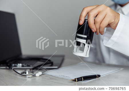 Male doctor in public medical office is stamping medical document. Healthcare concept Male doctor in public medical office is stamping medical document. Healthcare concept 70698765