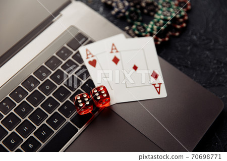 Chips, red dices and playing cards with aces for poker online or casino gambling on laptop keyboard top view. Online casino concept Chips, red dices and playing cards with aces for poker online or casino gambling on laptop keyboard top view. Online casino concept 70698771