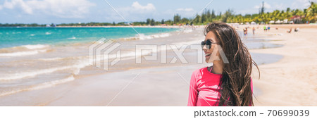 Happy vacation tourist woman relaxing on Puerto Rico beach banner panorama. Smiling young Asian girl in the sun, in sunglasses. 70699039
