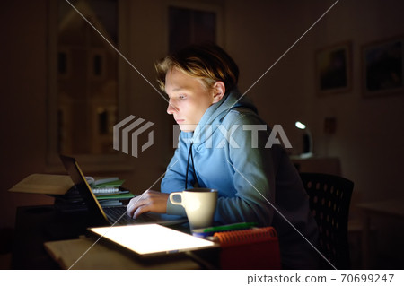 Concentrated young man working night at home office with laptop and tablet pc.  70699247