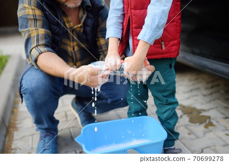 Preschooler boy helping his father washing family car. Little dad helper. Preschooler boy helping his father washing family car. Little dad helper. 70699278