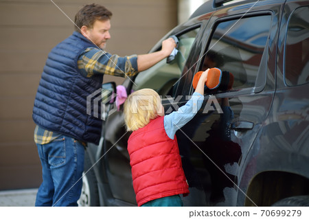 Preschooler boy helping his father washing family car. Little dad helper. Preschooler boy helping his father washing family car. Little dad helper. 70699279