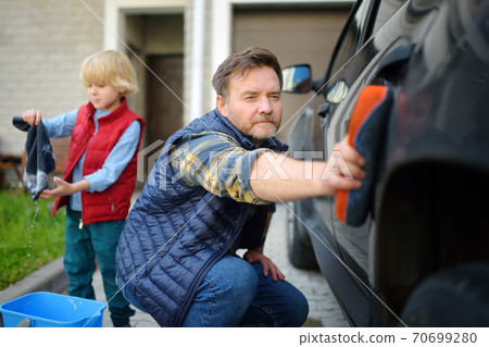 Preschooler boy helping his father washing family car. Little dad helper. Preschooler boy helping his father washing family car. Little dad helper. 70699280