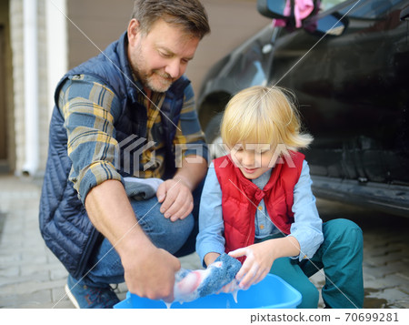 Preschooler boy helping his father washing family car. Little dad helper. 70699281