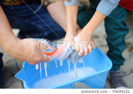 Preschooler boy helping his father washing family car. Little dad helper. Preschooler boy helping his father washing family car. Little dad helper. 70699282