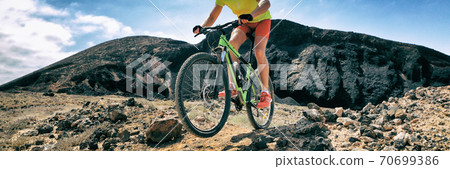 Mountain bike MTB biking athlete man in mountains landscape jumping riding bicycle. Professional bicycle rider training outdoors. Sport and fitness panoramic banner background. 70699386