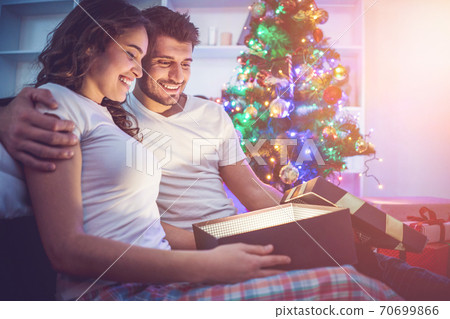 The happy man and a woman open the light box near the christmas tree The happy man and a woman open the light box near the christmas tree 70699866