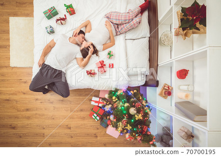 The kissing couple lay on the bed with gifts. view from above The kissing couple lay on the bed with gifts. view from above 70700195