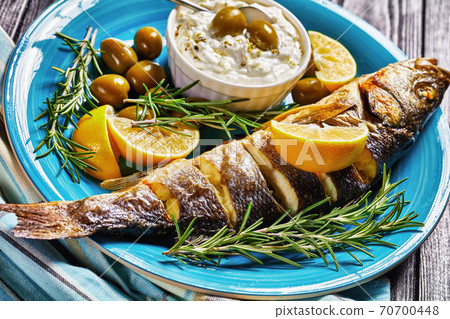 Seabass fish on a plate with lemon and rosemary Seabass fish on a plate with lemon and rosemary 70700448