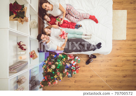 The happy family lay on the bed near a christmas tree. view from above The happy family lay on the bed near a christmas tree. view from above 70700572
