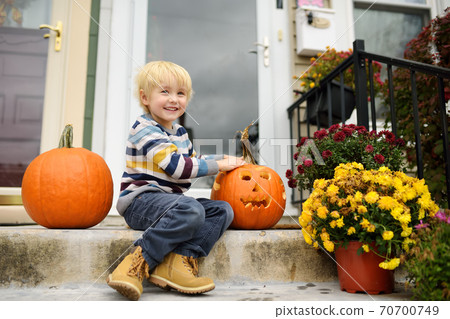 Little child sitting on porch of his home and waiting for the traditional "trick or treat" Little child sitting on porch of his home and waiting for the traditional "trick or treat" 70700749