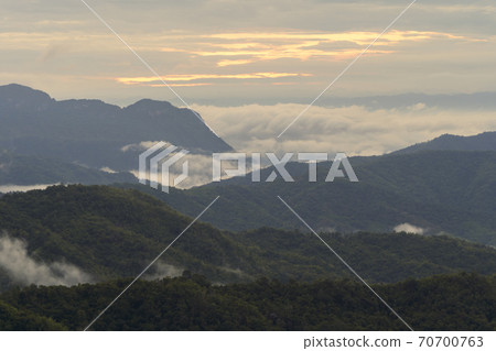 Aerial view of sunset above fluffy sea fog misty clouds with mountain hill from Phu Tub Berk, Khao Kho, Phetchabun with sunlight. Abstract nature landscape background at twilight time. Aerial view of sunset above fluffy sea fog misty clouds with mountain hill from Phu Tub Berk, Khao Kho, Phetchabun with sunlight. Abstract nature landscape background at twilight time. 70700763