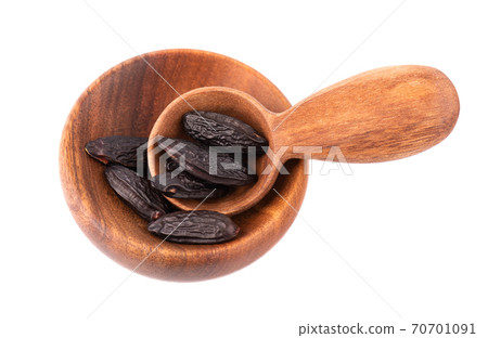 Tonka beans in wooden bowl and spoon, isolated on white background. Bean of Dipteryx odorata, cumaru or kumaru. Fresh aroma tonka beans. 70701091