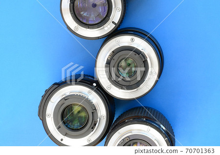 Several photographic lenses lie on a bright blue background. Space for text Several photographic lenses lie on a bright blue background. Space for text 70701363
