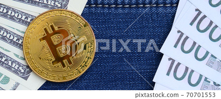 Golden Bitcoin, dollar and euro bills lies on a blue jeans fabric. New virtual money 70701553