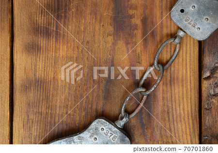 Old and rusty police handcuffs lie on a scratched wooden surface. The concept of an old crime Old and rusty police handcuffs lie on a scratched wooden surface. The concept of an old crime 70701860