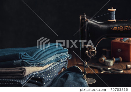Antique sewing machine and stack of fabrics. Copy space for text. 70703816