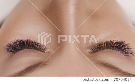 Eyelash Extension Procedure. Close up view of beautiful female eye with long eyelashes, smooth healthy skin. Eyelash Extension Procedure. Close up view of beautiful female eye with long eyelashes, smooth healthy skin. 70704054