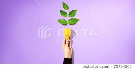 Person holding a lightbulbs with green leaves Person holding a lightbulbs with green leaves 70704863