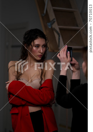 A young beautiful oriental woman with long black hair in a red jacket against a black background. The fashion model poses in the studio. 70710013