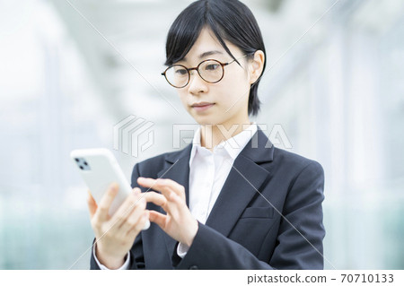 一個穿著智能手機的西裝的年輕女子 70710133