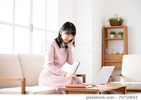 Young woman teleworking operating a smartphone at home Young woman teleworking operating a smartphone at home 70710683