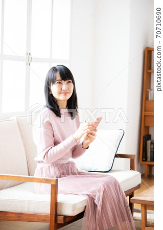 Young woman operating a smartphone at home Young woman operating a smartphone at home 70710690