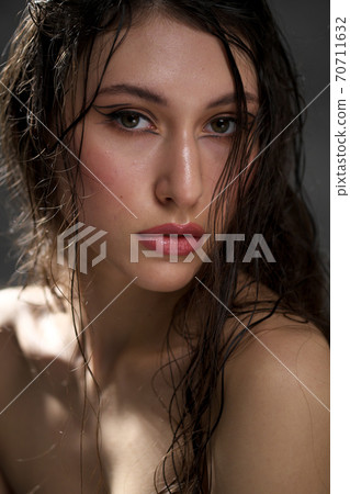 The face of a beautiful young girl with wet black hair close-up. Eastern appearance. Nude makeup, natural skin. 70711632